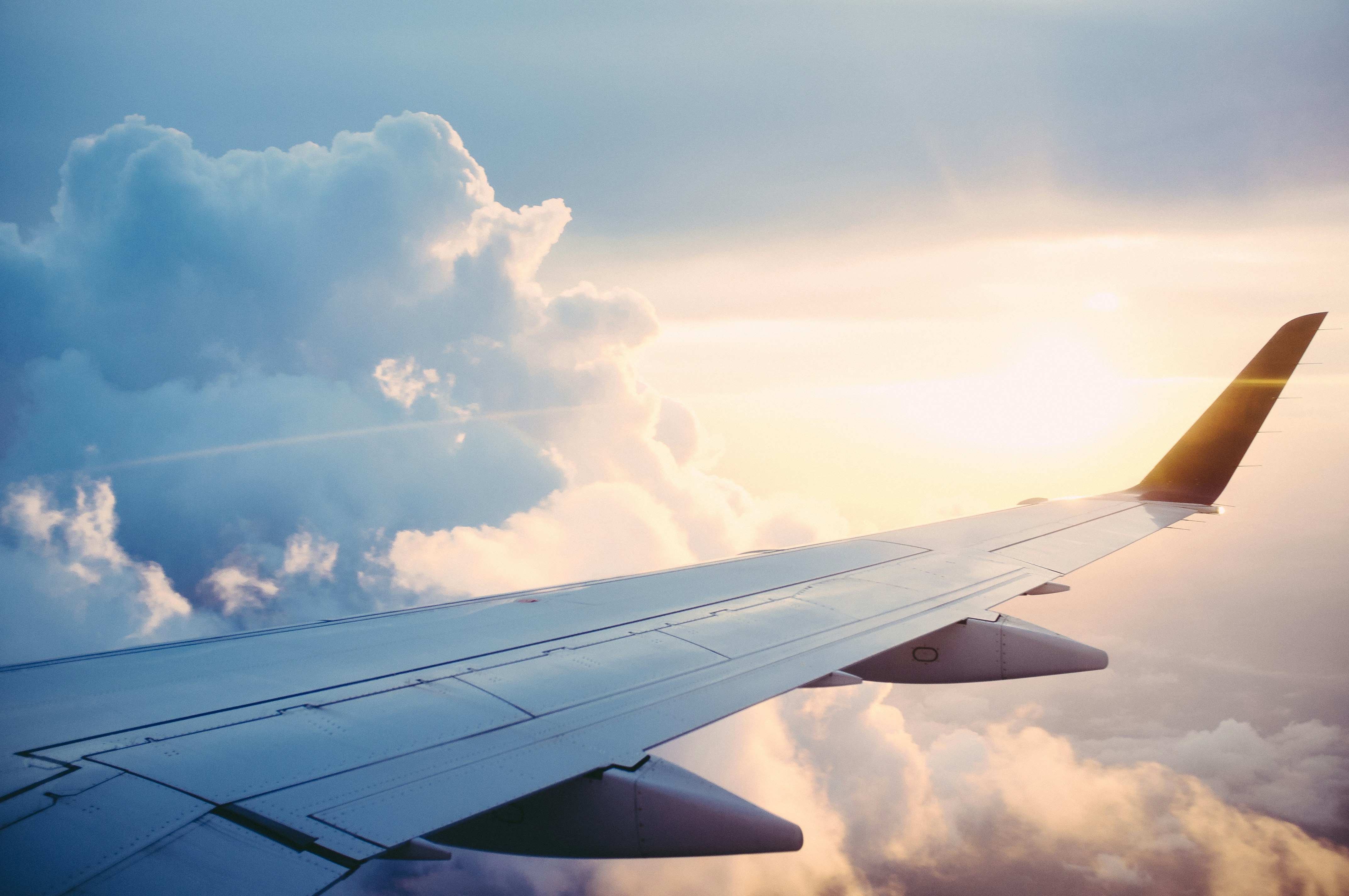Ein Flugzeugflügel über den Wolken mit untergehender Sonne