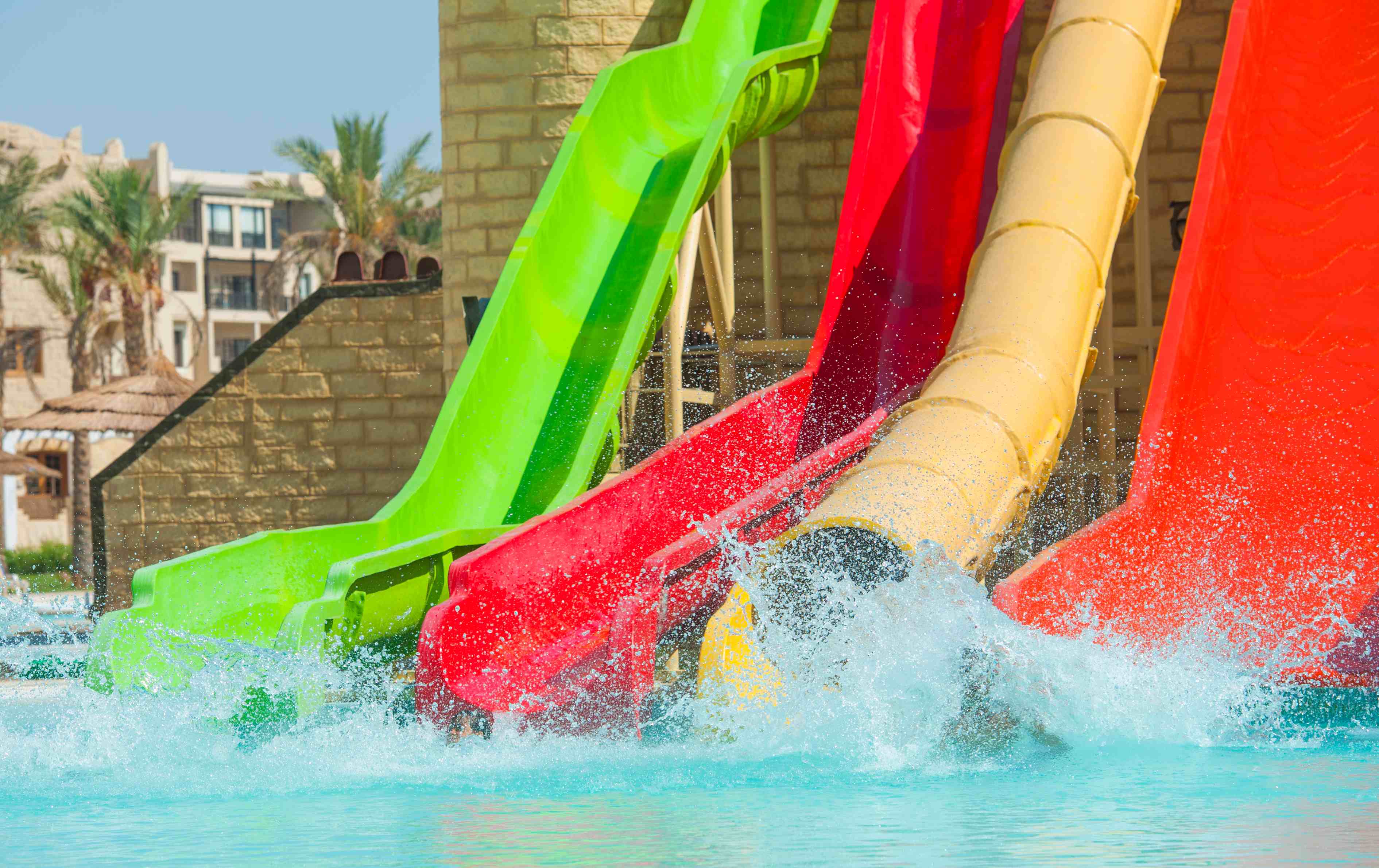 vier-bunte-wasserrutschcen-enden-in-einem-pool