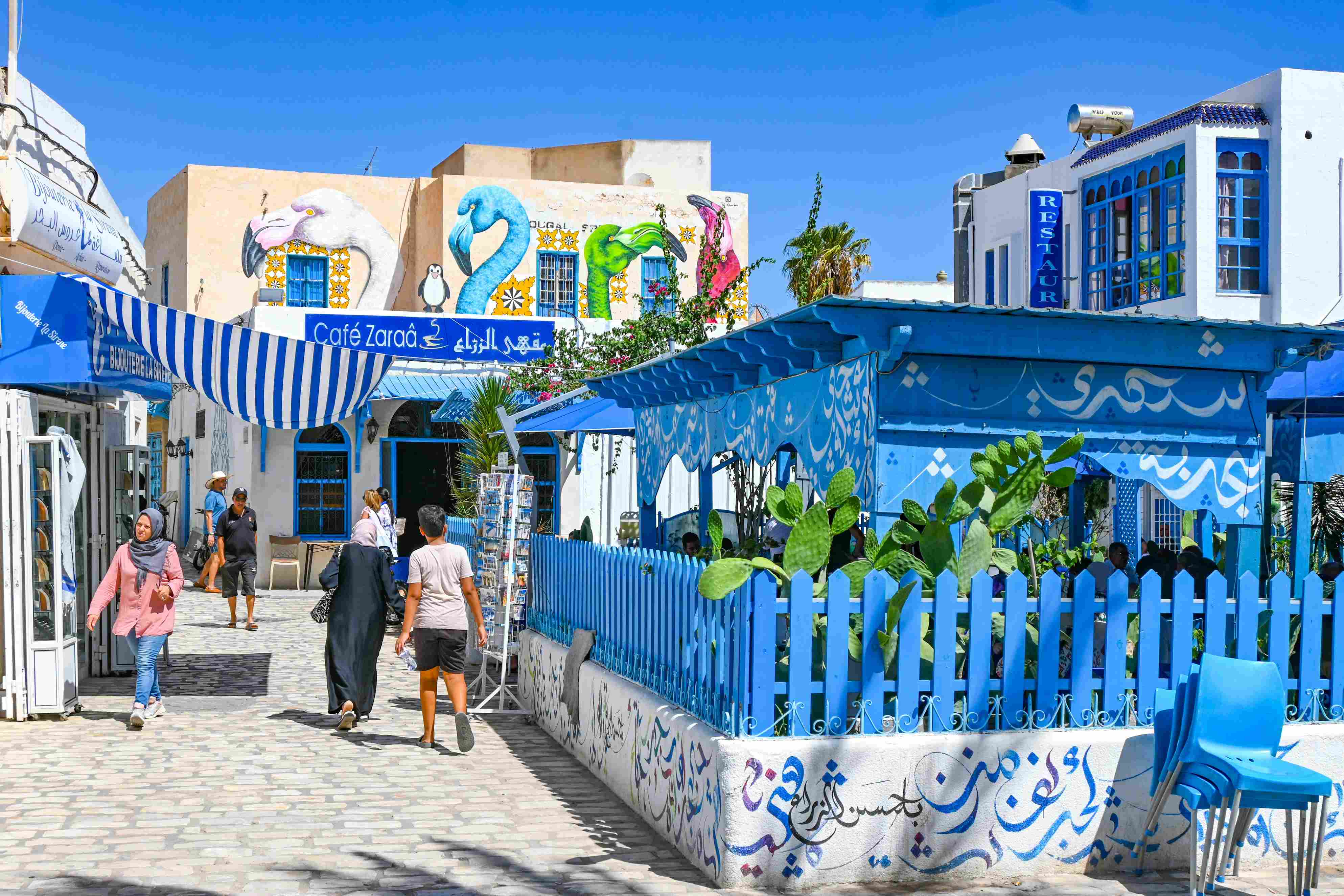 Ein Gasse mit Kopfsteinpflaster führt durch eine blau-weiße Stadt