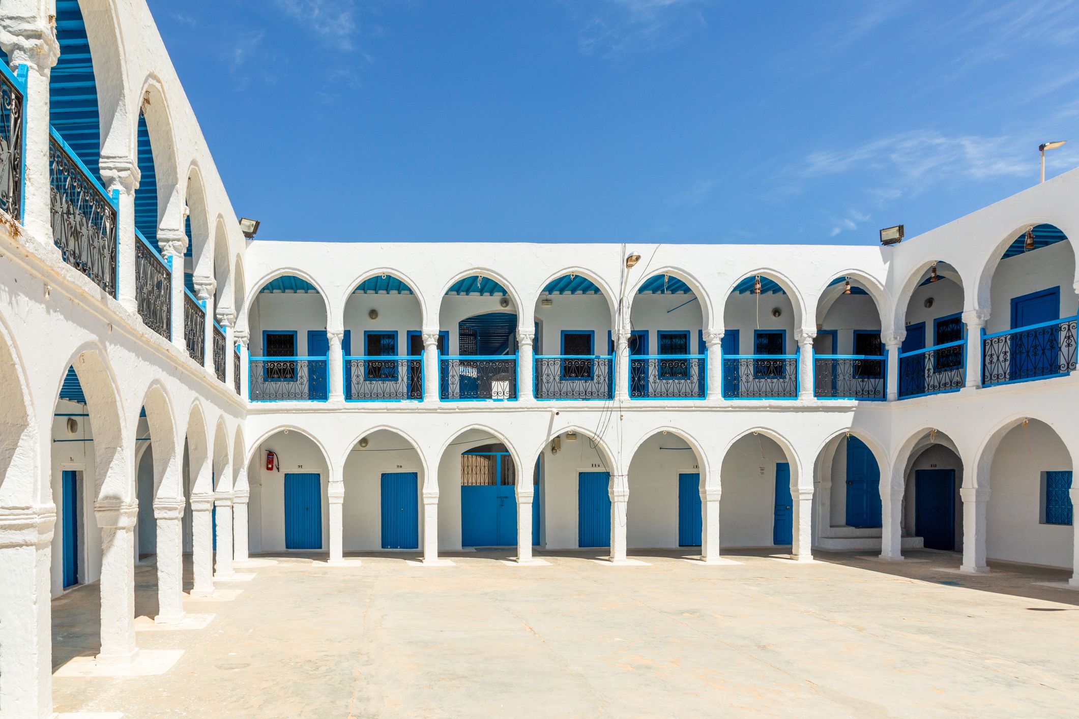 el-ghriba-synagoge Der Innenhof einer blau-weißen Synagoge unter blauem Himmel