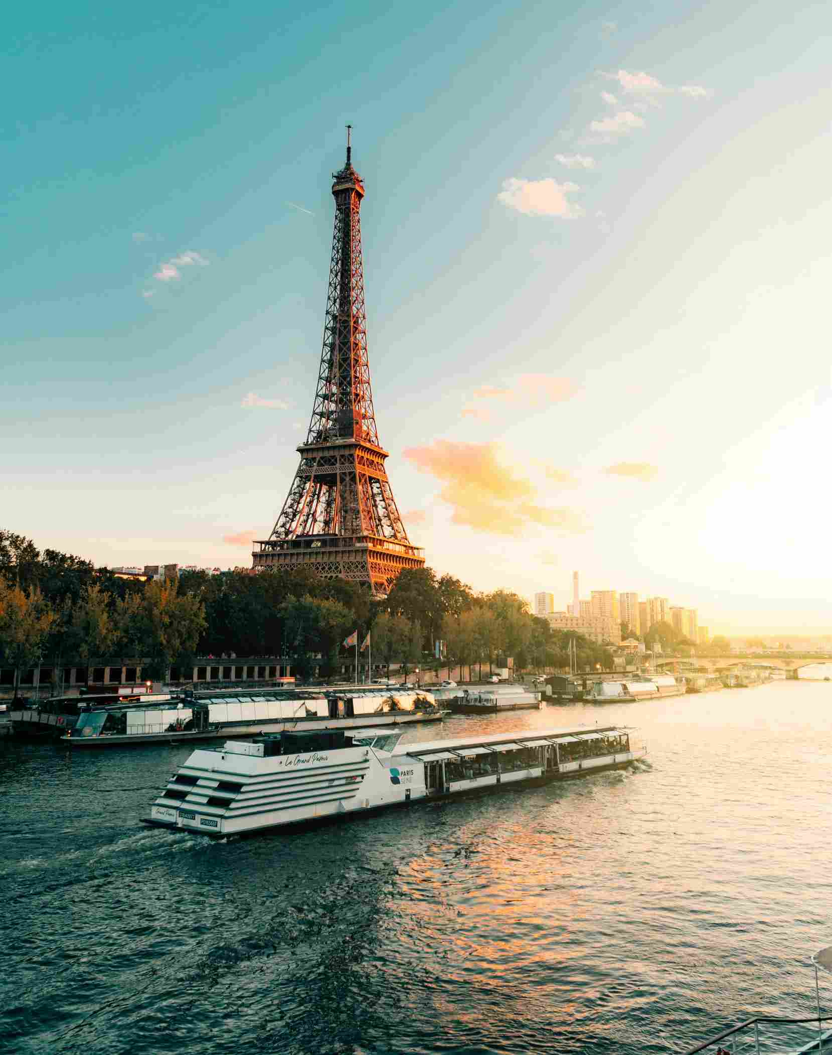 Ein weißes Flusskreuzfahrtschiff fährt auf der Seine am Eifelturm vorbei