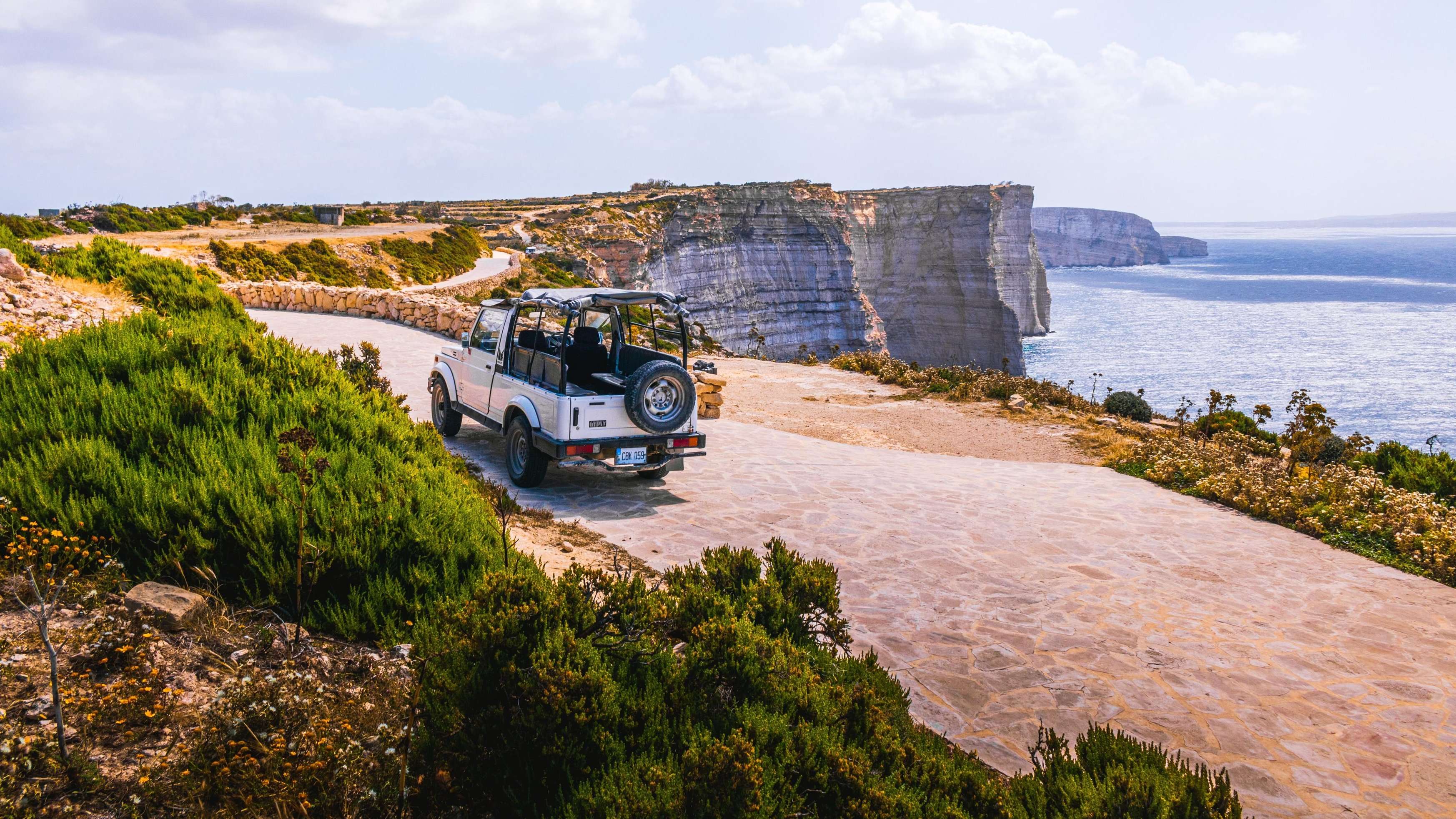 gozo-klippe-auto an-einer-steilen-klippe-fährt-ein-jeepartiges-auto-entlang