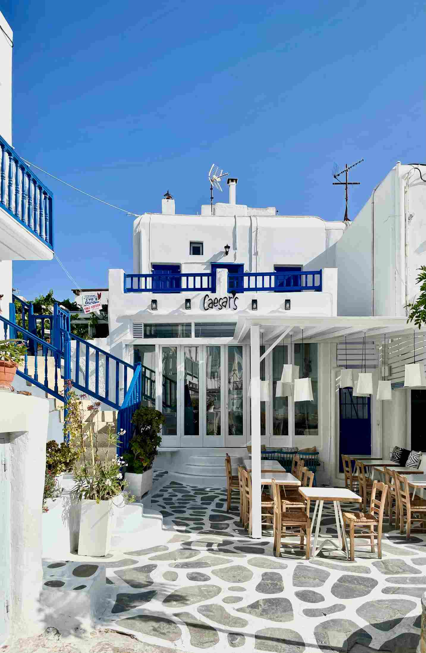 Ein weißes Haus mit blauen Akzenten und Außengastronomie