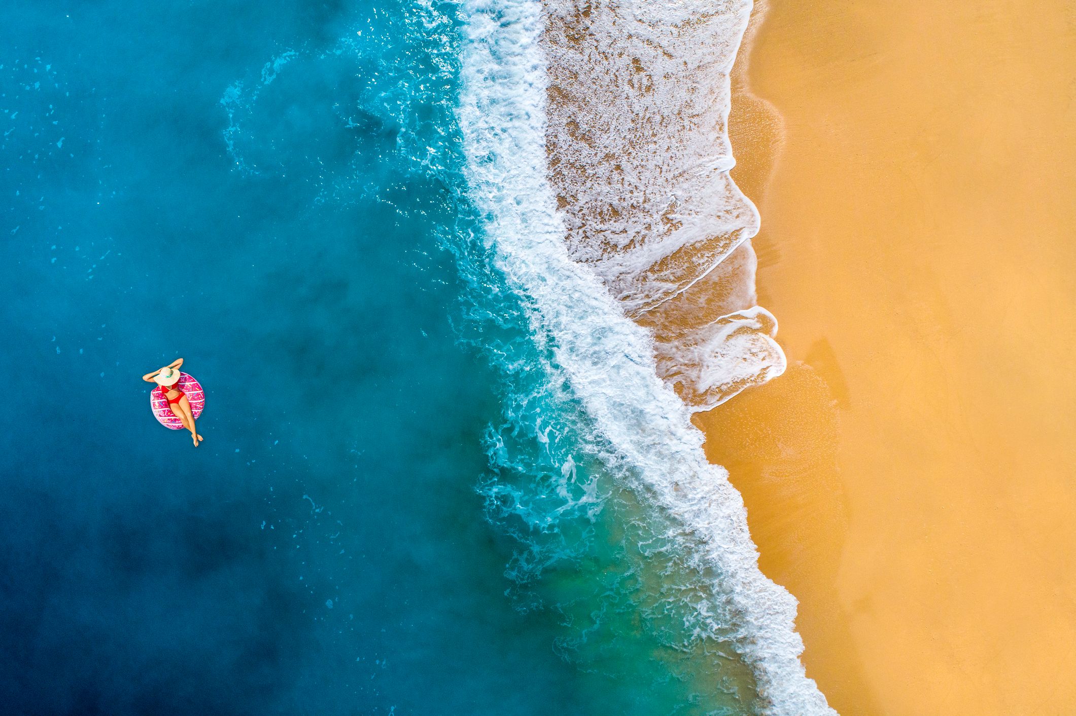 top-ten-günstige-urlaubsziele-2026 eine-frau-im-pinken-schwimmreifen-liegt-im-offenen-meer