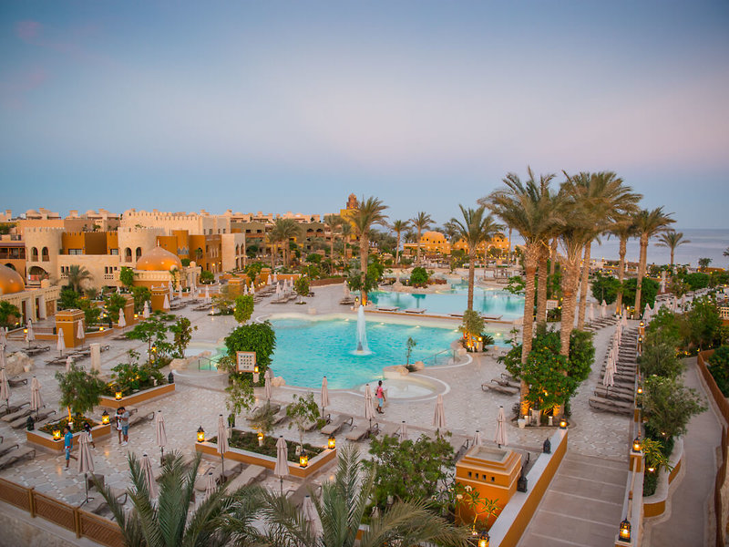 Außenbereich des Grand Waterworld Makadi Poolanlage mit Palmen, Sonnenliegen und Hotelgebäuden