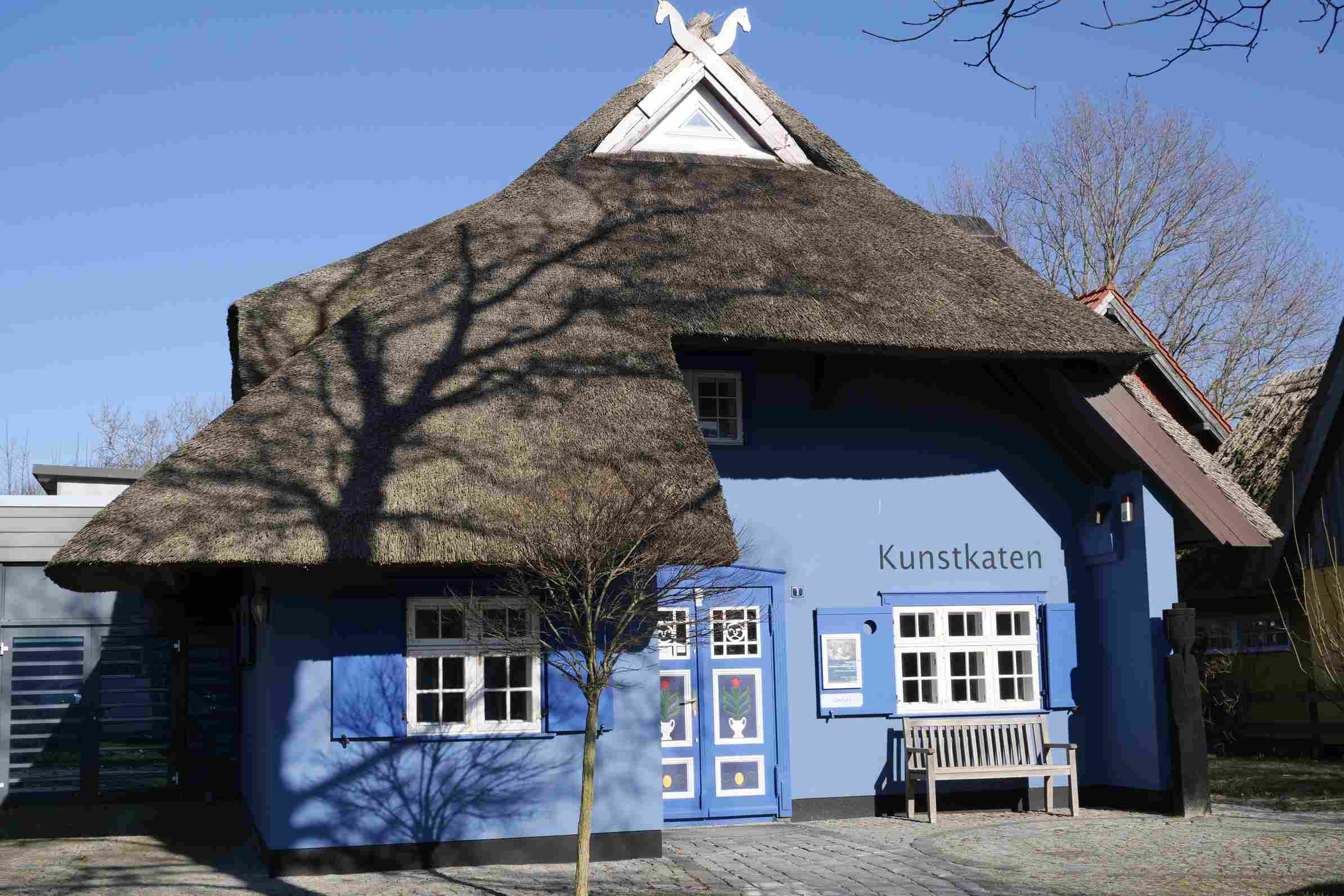Ein blaues Haus mit verzierter Tür und der Aufschrift "Kunstkaten"
