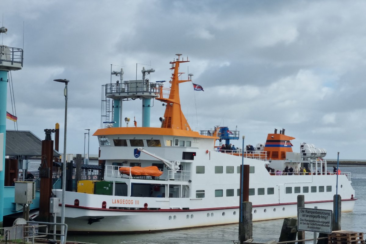 Weißes Fährschiff liegt am Kai im Hafen