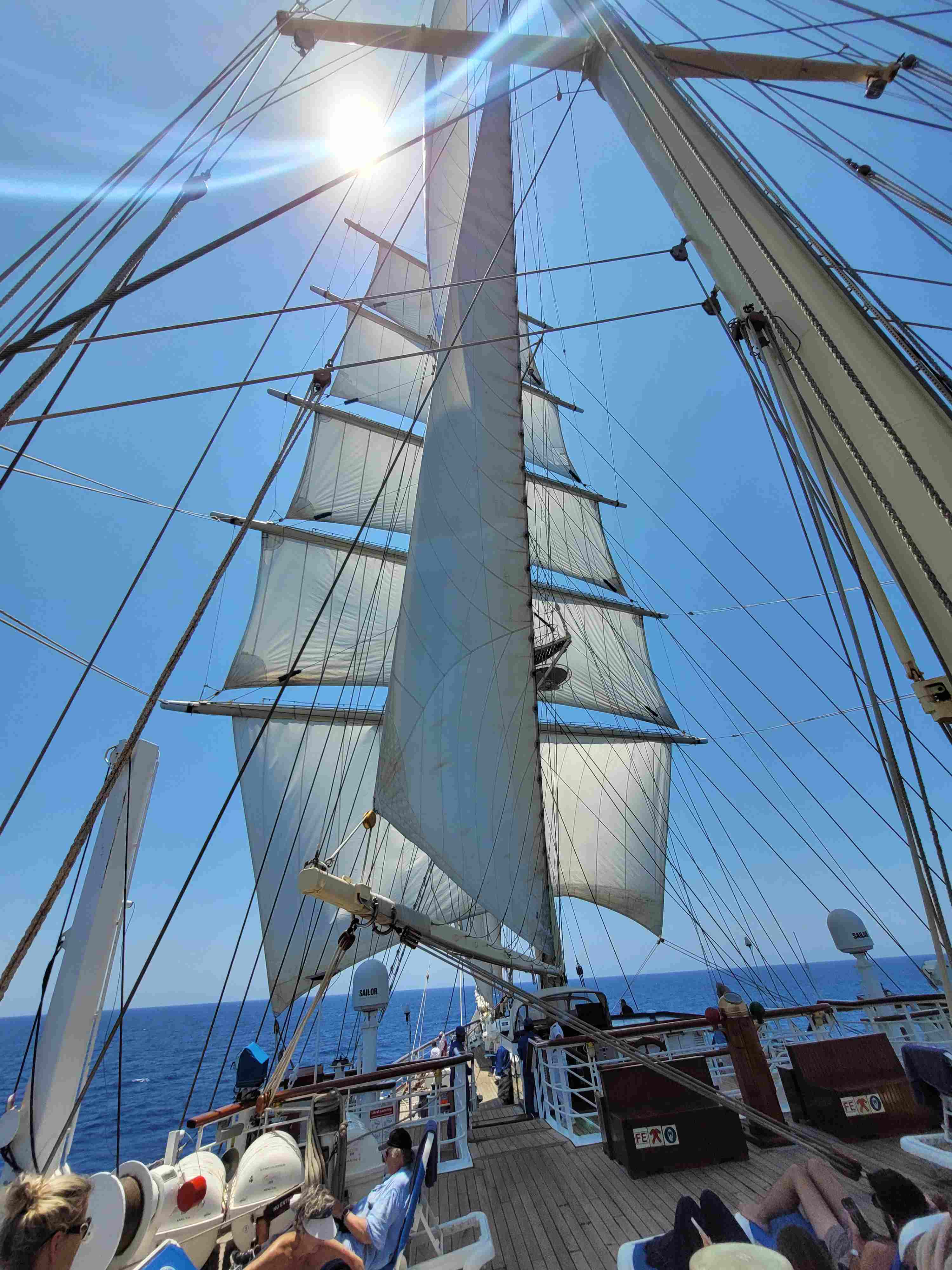 Der weiße Mast eines Segelschiffs ragt in den strahlend blauen Himmel
