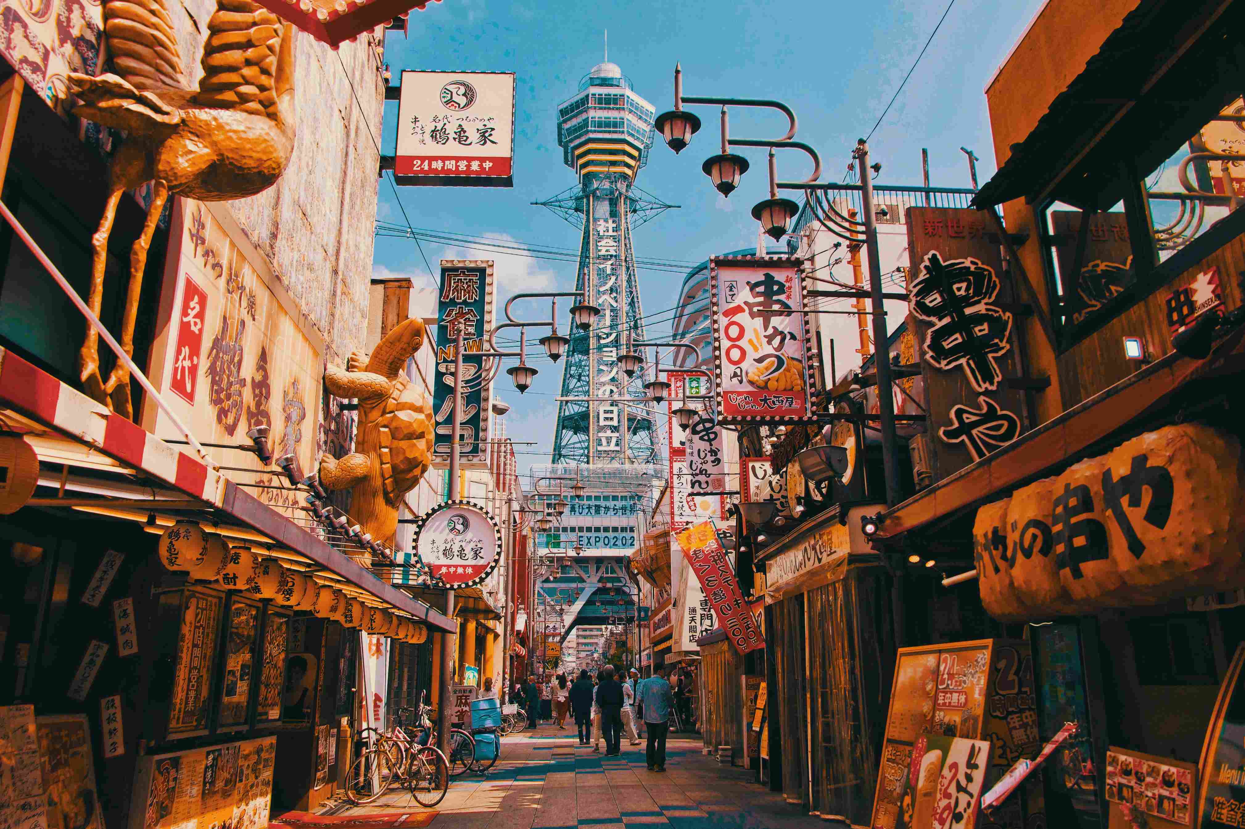 Eine Straße mit vielen japanischen Schildern, Figuren und hohen Gebäuden
