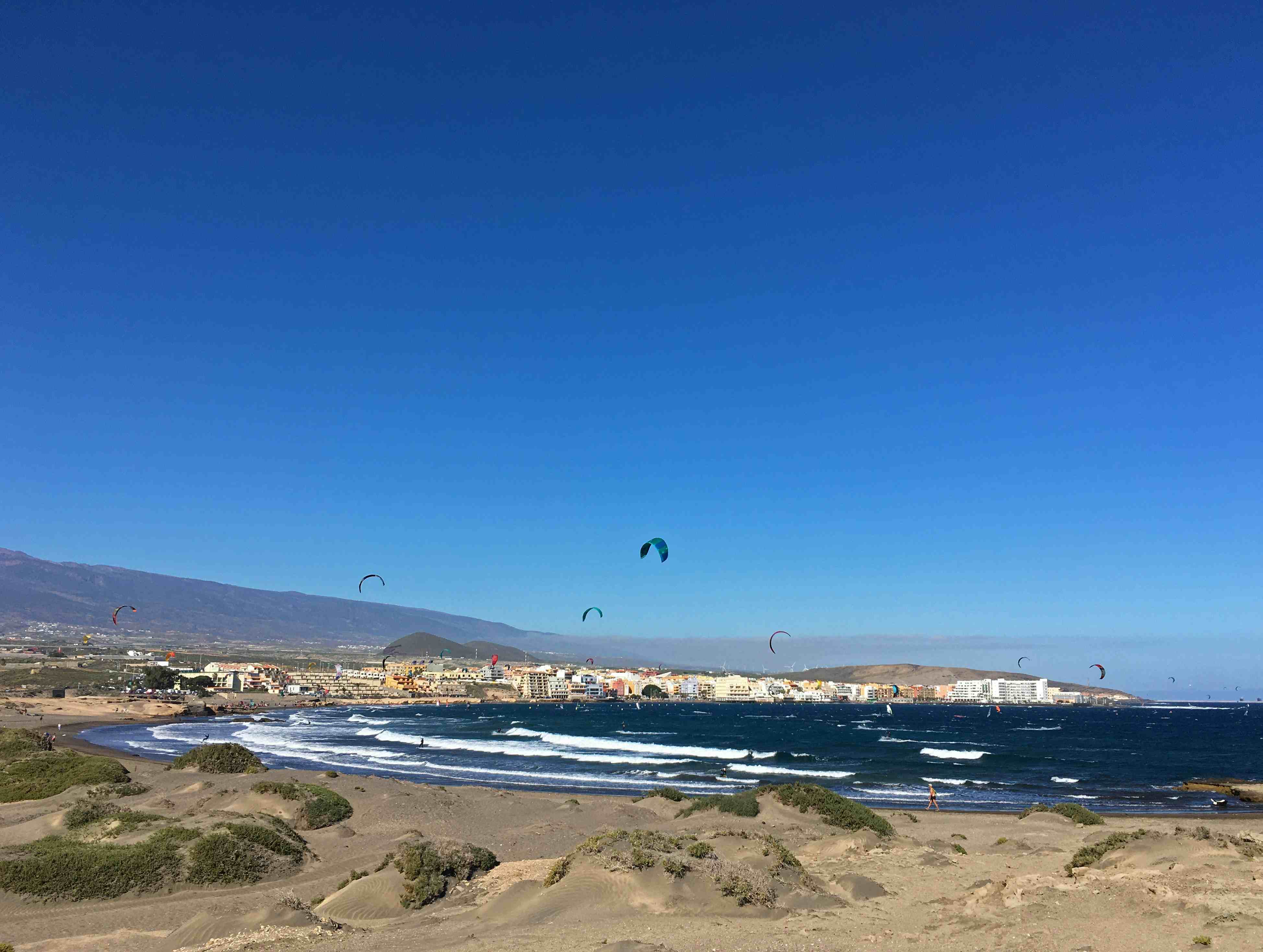 teneriffa-wassersport An einem belebten Strand in Stadtnähe sieht man viele Kitesurfer