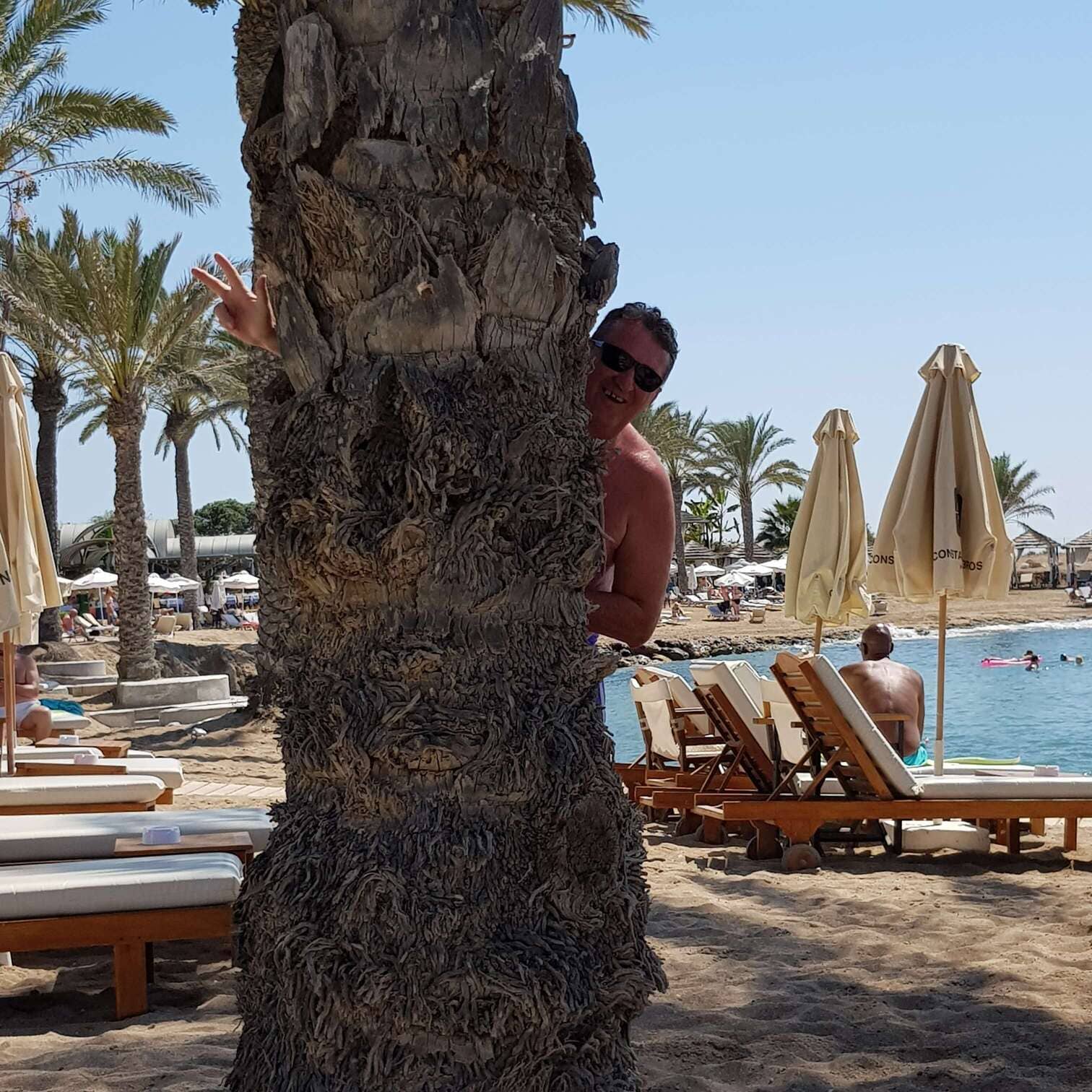 Strandurlaub auf Zypern Gründer Richard steht hinter einer Palme am Strand