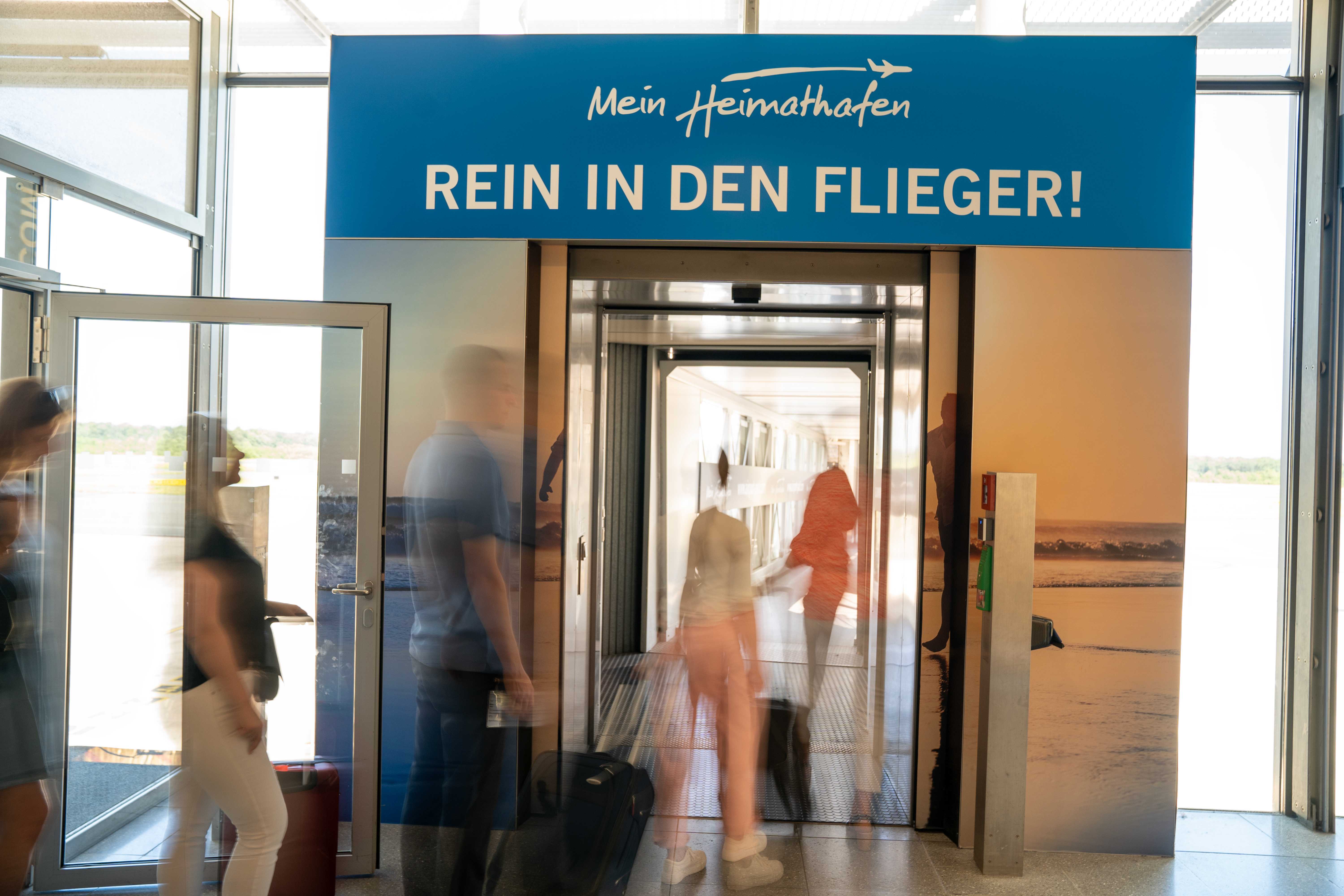 Frau steht vor Abflugtafel mit dem Schriftzug Kassel Calden