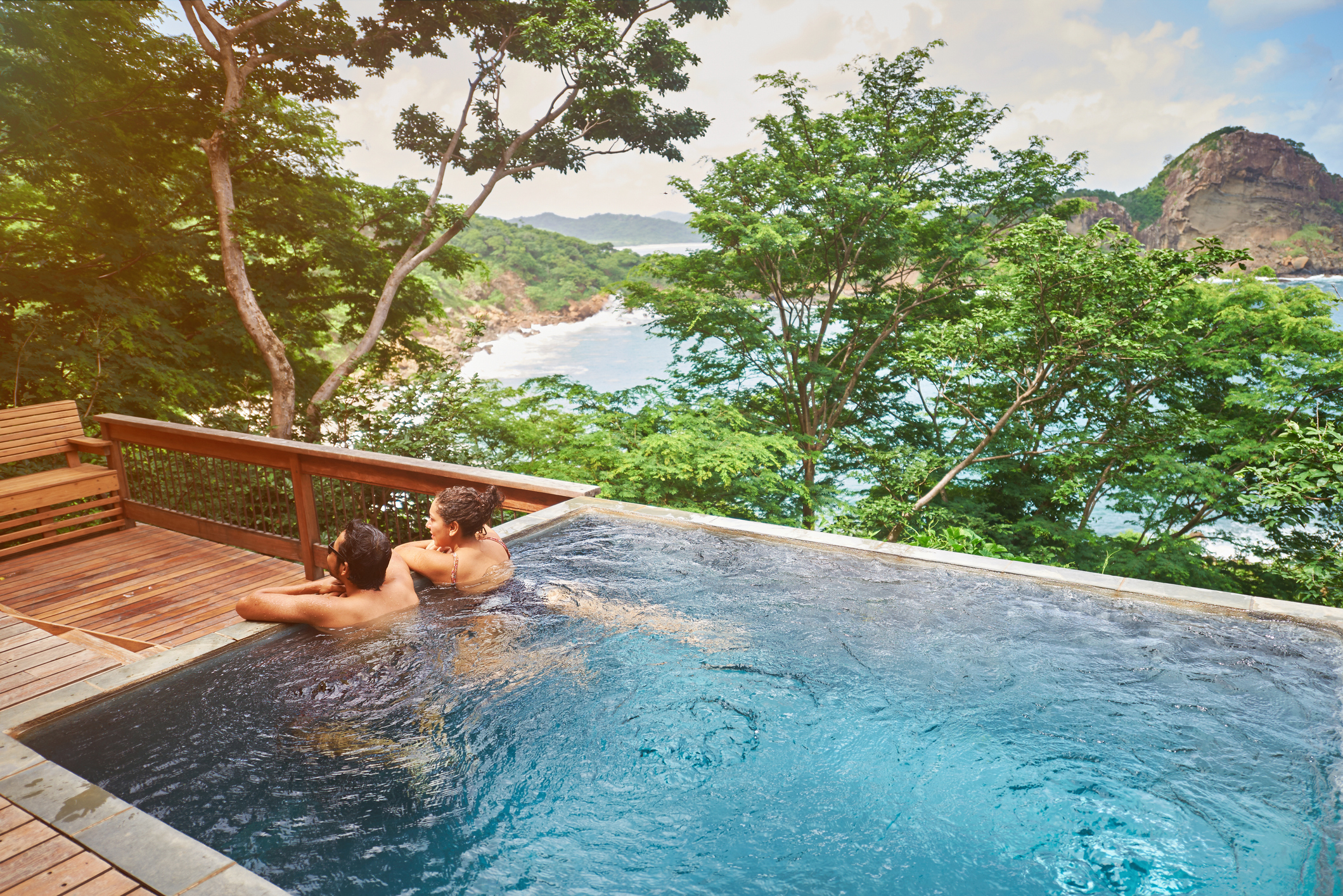 Pärchen Im Pool mit Blick auf eine Meeresbucht