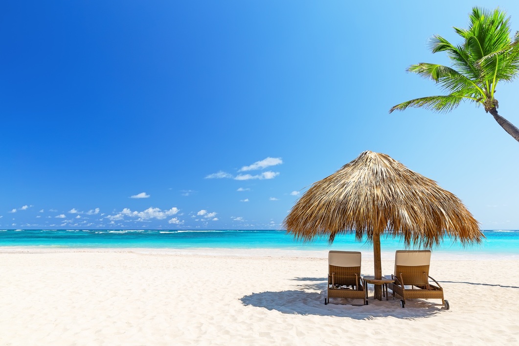 Urlaub im August Ein menschenleerer Strand mit Sonnenliegen und Sonnenschirm