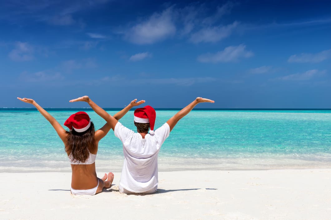 Weihnachtsurlaub Pärchen mit Weihnachtsmann Mützen am Strand