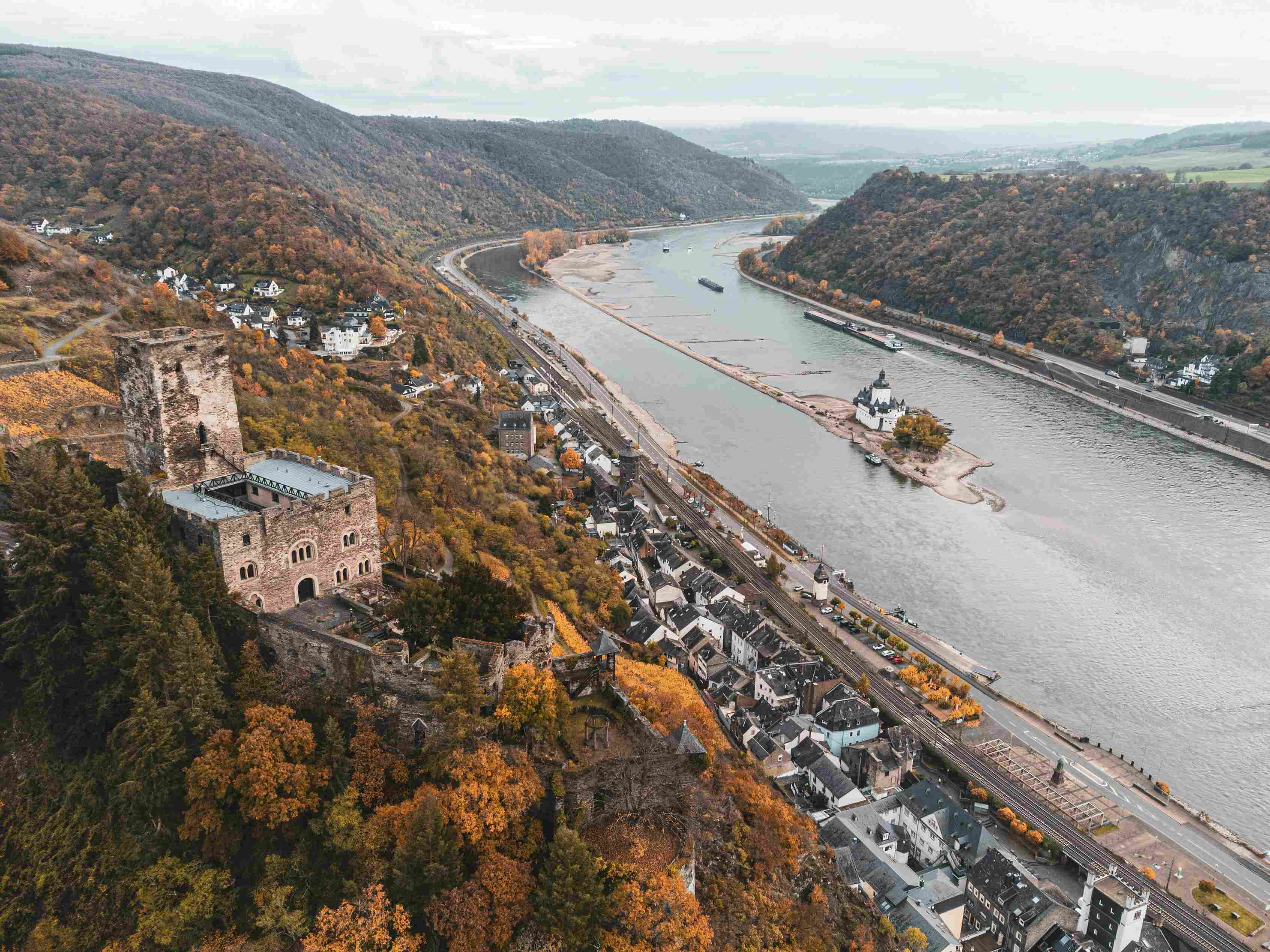 rhein-flusskreuzfahrt Eine herbstliche Landschaft mit Burgen, in der Mitte der Fluss Rhein