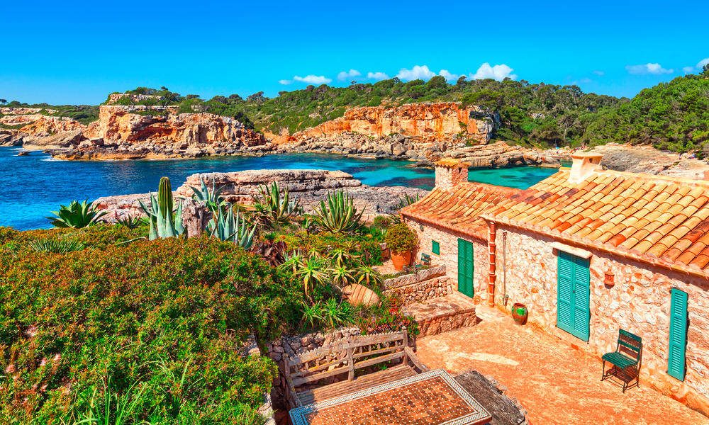 Ein mediterranes Haus mit Kakteen und begrüntem Garten grenzt direkt an die Küste.