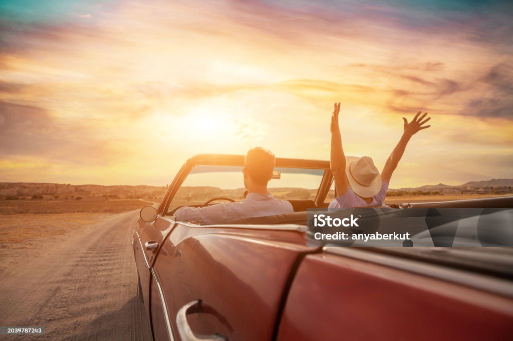 Ein Pärchen sitzt im Cabrio im Abendlicht