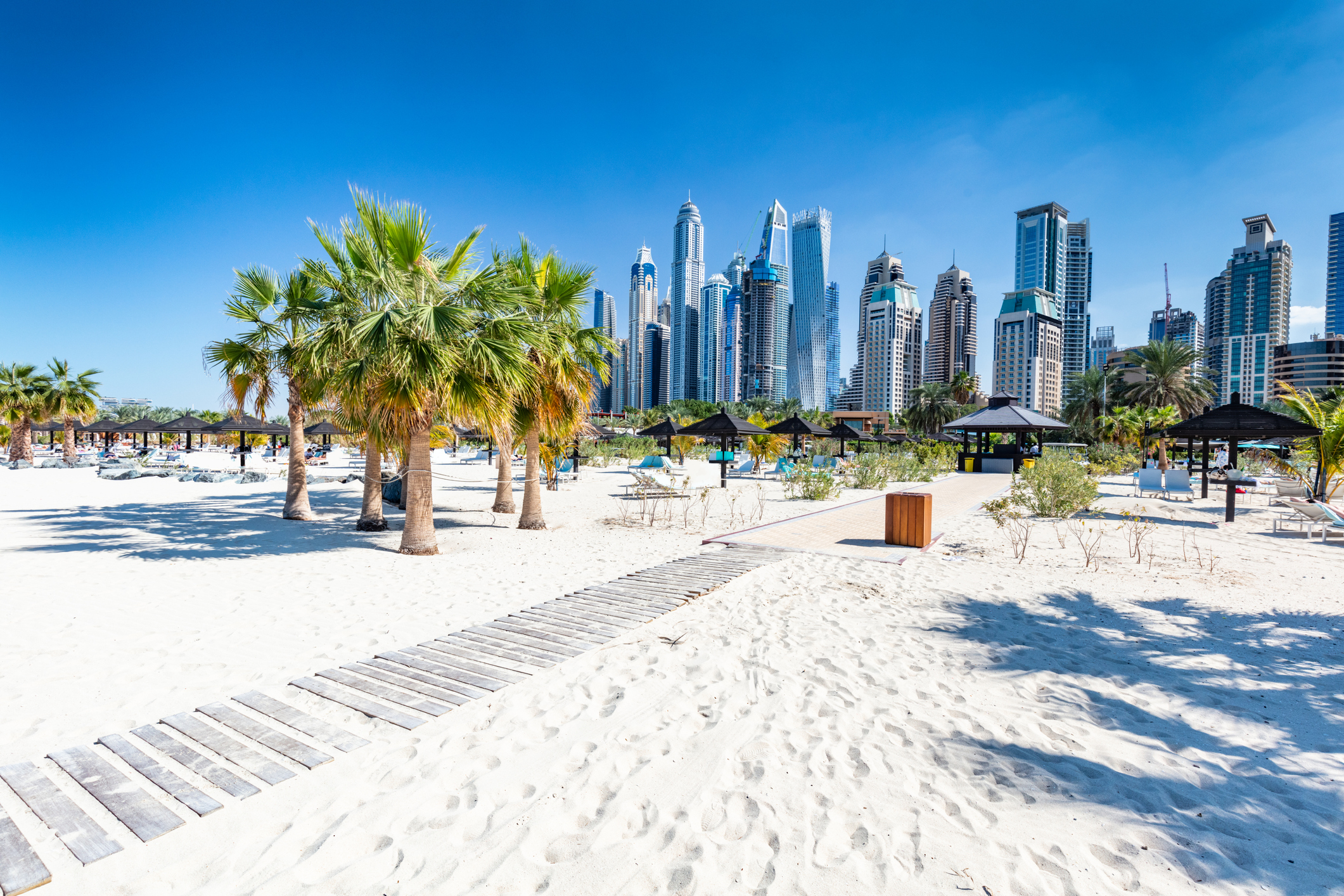 Blick vom Strand mit Palmen auf die Skyline von Dubai mit Wolkenkratzern