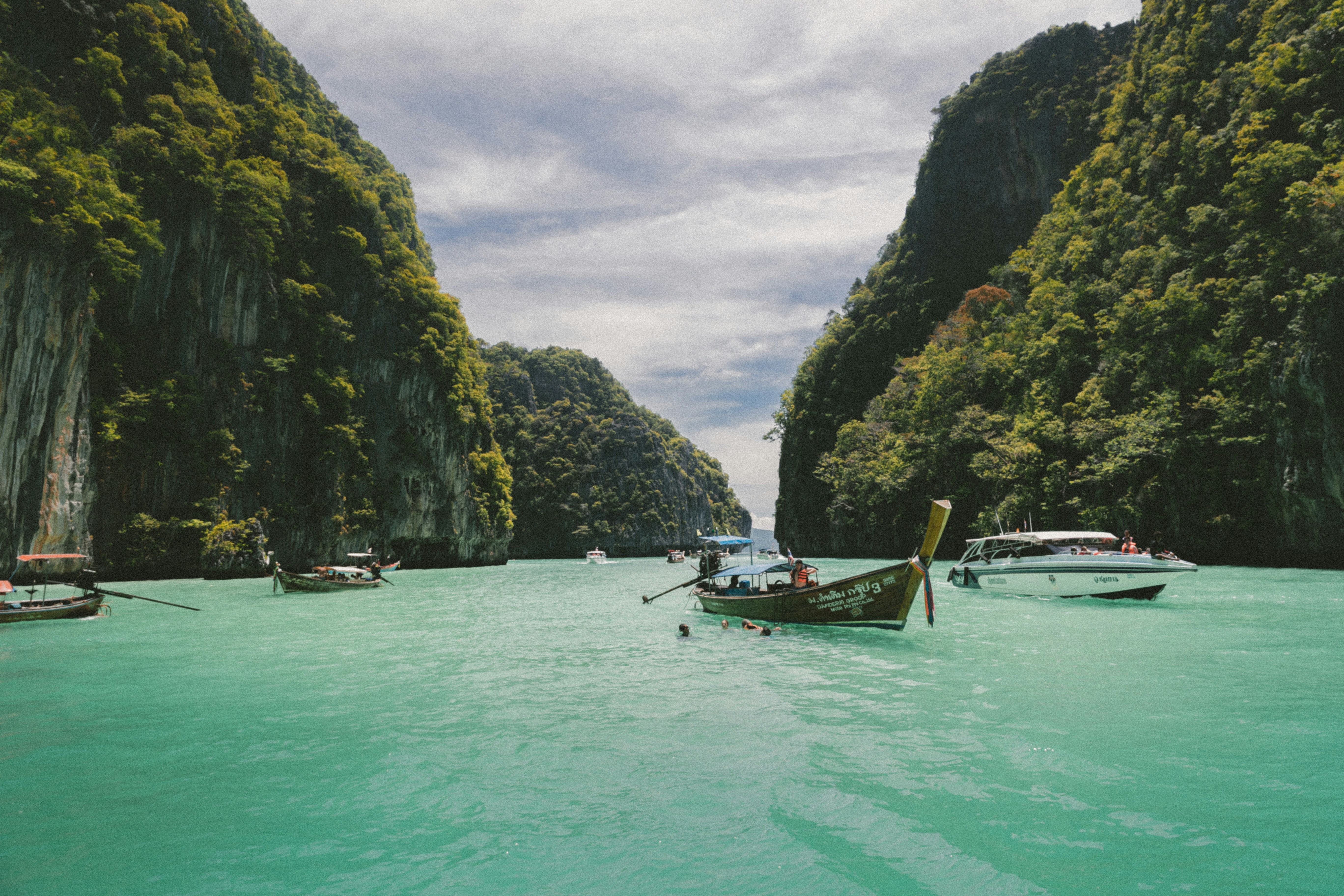 Thailand typische Fischerboote zwischen grünen Tuffsteinfelsen im Meer