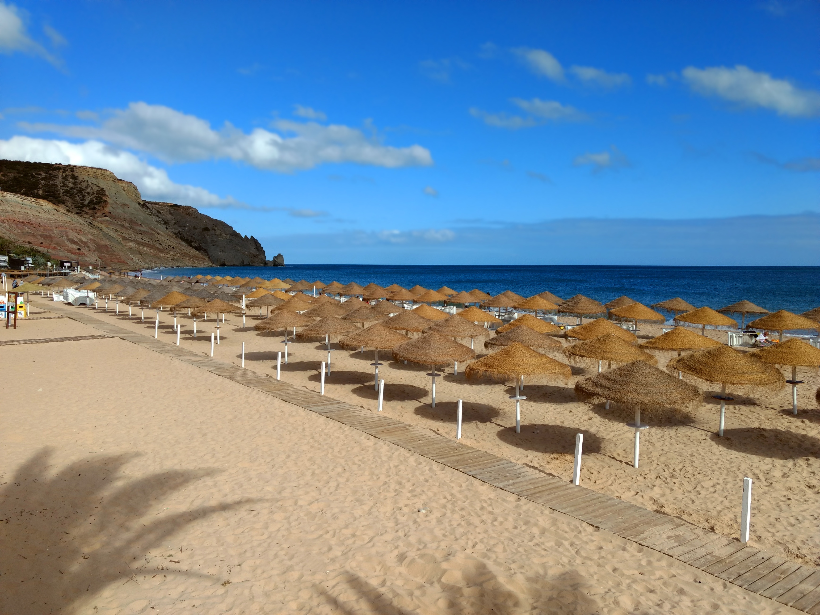 Goldgelber Strand mit Sonnenschirmen und Liegen am Meer