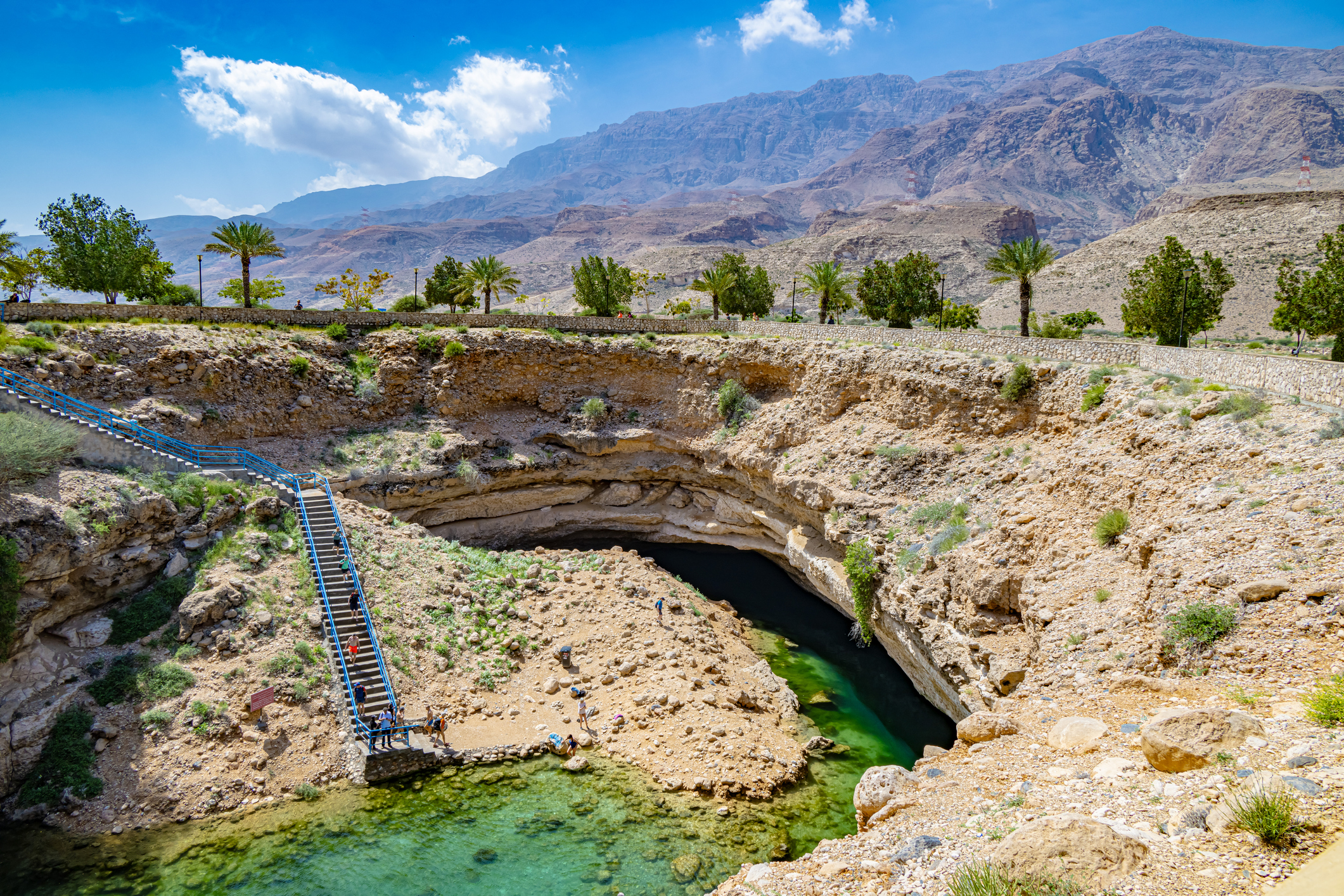 Oman Sinkhole felsige Landschaft mit einem Wasserloch, Steinen und Palmen