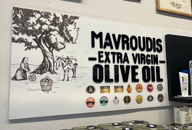 Mavroudis Olivenölproduktion Ein Schild mit vielen Abzeichen und Siegeln und der Aufrschrift "Mavroudis"