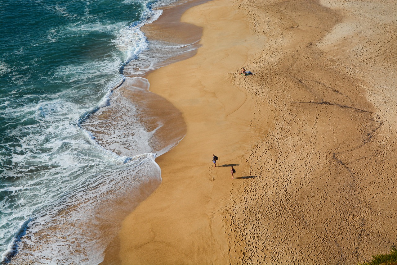 Goldgelber Sandstrand mit Menschen und Meeresgischt