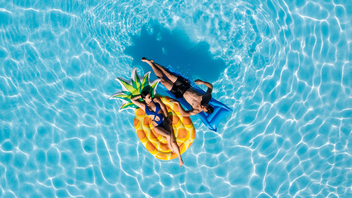Ein Pärchen auf Luftmatratzen im Pool