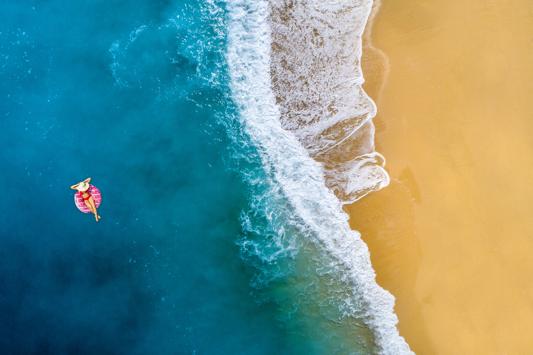 Top 10 günstigste Reiseländer 2027 Frau liegt im pinken Schwimmreifen im Meer