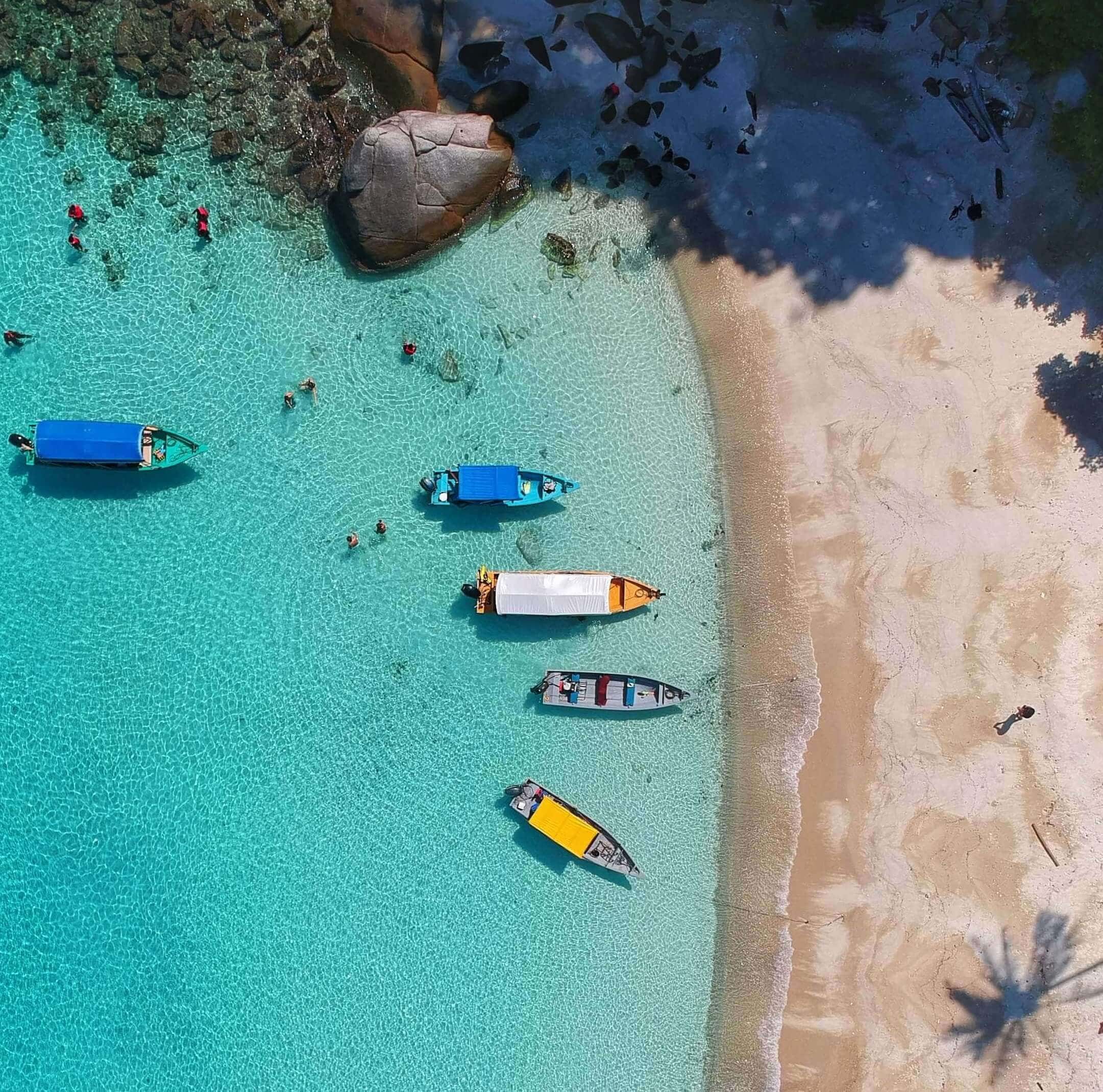 Urlaub im Oktober Blick auf Strand mit kristallklarem Waser und Booten