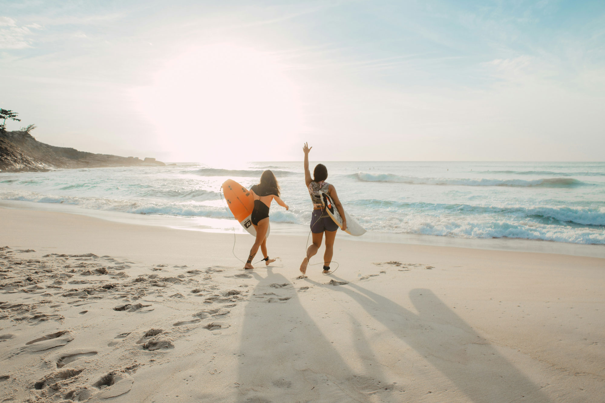 2 junge Frauen mit Surfbrett am Strand